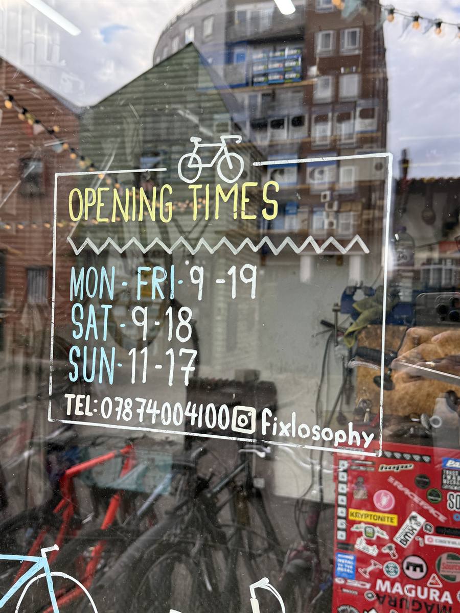 Hand-painted sign showing the shop's opening times